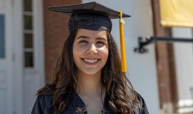 smiling woman is wearing a graduation cap and gown 